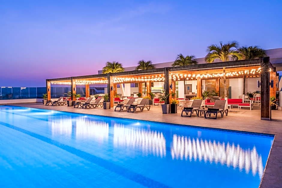 Rooftop con piscina y cabañas iluminadas al atardecer